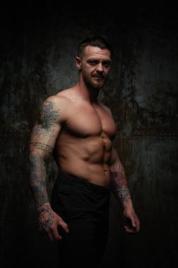 Gömleksiz kaslı genç adam grunge duvar arka planı poz 