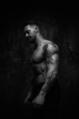 Siyah ve beyaz fotoğraf gömleksiz kaslı genç adamın grunge duvar arka planı poz 