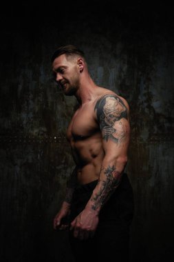 Gömleksiz kaslı genç adam grunge duvar arka planı poz 