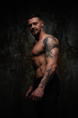 Gömleksiz kaslı genç adam grunge duvar arka planı poz 