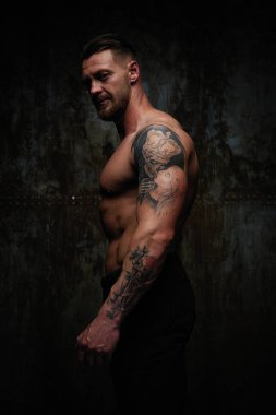 Gömleksiz kaslı genç adam grunge duvar arka planı poz 