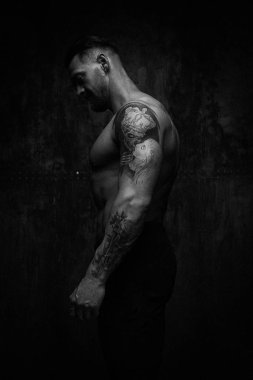 Siyah ve beyaz fotoğraf gömleksiz kaslı genç adamın grunge duvar arka planı poz 