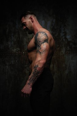 Gömleksiz kaslı genç adam grunge duvar arka planı poz 