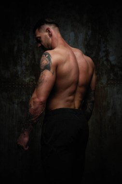 Gömleksiz kaslı genç adam grunge duvar arka planı poz 