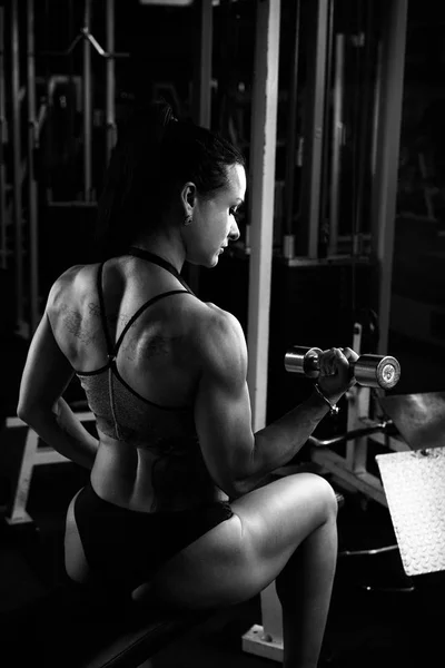 黑色和白色照片的年轻黑发肌肉妇女在健身房锻炼 — 图库照片