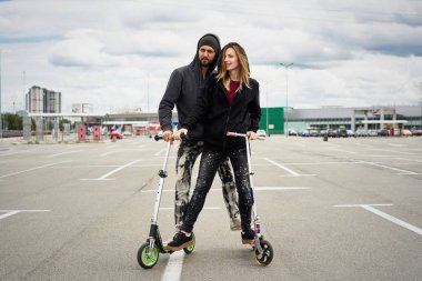 Kentsel arka plan üzerinde tekme scooter ile genç şık çift 