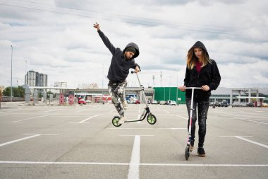 Kentsel arka plan üzerinde tekme scooter ile genç şık çift 