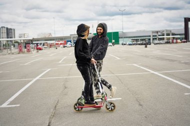 Kentsel arka plan üzerinde tekme scooter ile genç şık çift 