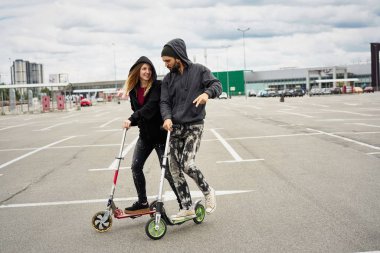Kentsel arka plan üzerinde tekme scooter ile genç şık çift 