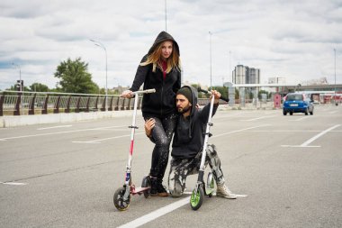 Kentsel arka plan üzerinde tekme scooter ile genç şık çift 