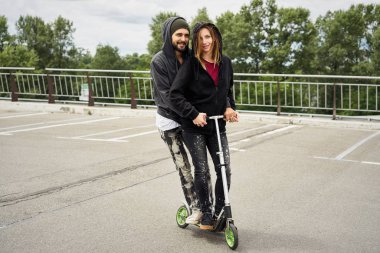 Kentsel arka plan üzerinde tekme scooter ile genç şık çift 