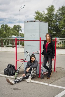 Kentsel arka plan üzerinde tekme scooter ile genç şık çift 