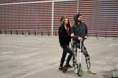 Kentsel arka plan üzerinde tekme scooter ile genç şık çift 