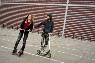 Kentsel arka plan üzerinde tekme scooter ile genç şık çift 