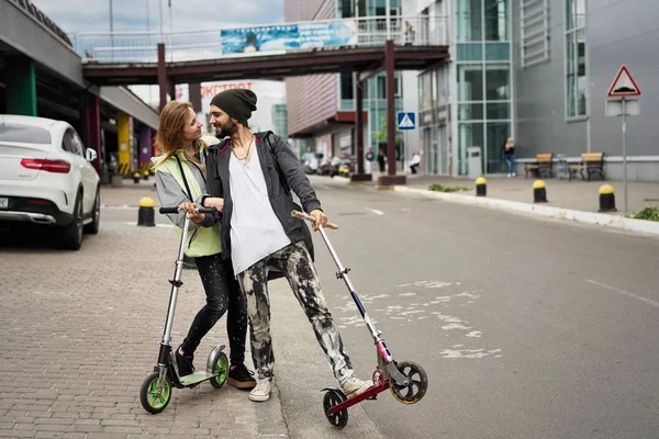 Kentsel arka plan üzerinde tekme scooter ile genç şık çift 