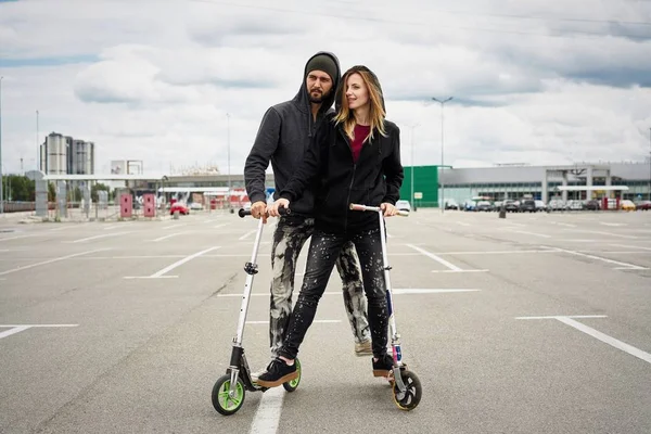 Kentsel arka plan üzerinde tekme scooter ile genç şık çift 