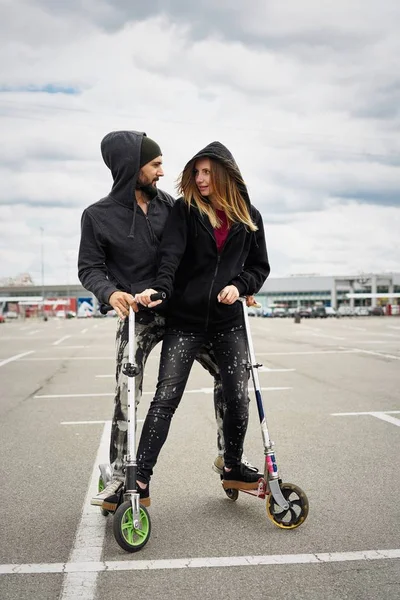 Kentsel arka plan üzerinde tekme scooter ile genç şık çift 