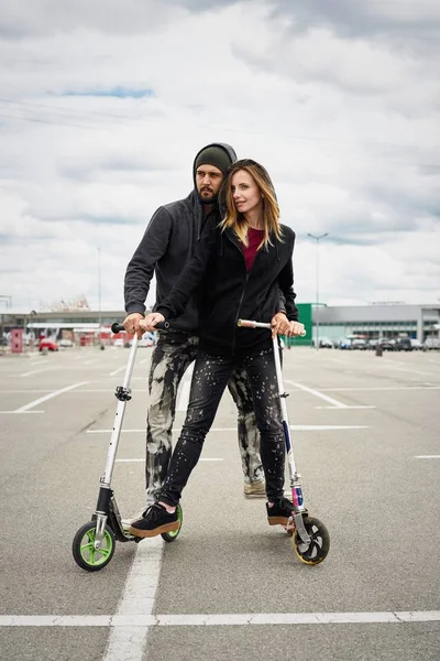 Kentsel arka plan üzerinde tekme scooter ile genç şık çift 