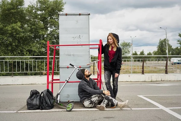 Kentsel arka plan üzerinde tekme scooter ile genç şık çift 