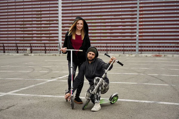 Kentsel arka plan üzerinde tekme scooter ile genç şık çift 