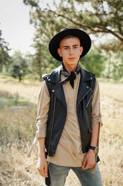 Yakışıklı genç adam rahat kıyafetler ve şık şapka açık havada poz 