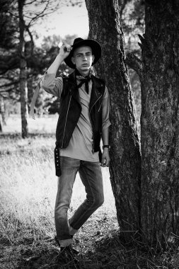 Yakışıklı genç adam rahat kıyafetler ve şık şapka açık havada poz 