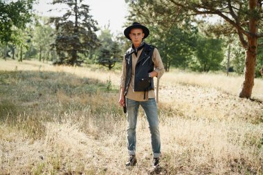 Yakışıklı genç adam rahat kıyafetler ve şık şapka açık havada poz 