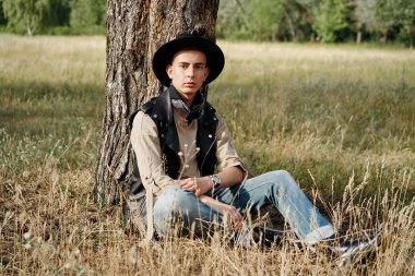 Yakışıklı genç adam rahat kıyafetler ve şık şapka açık havada poz 