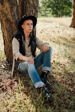 Yakışıklı genç adam rahat kıyafetler ve şık şapka açık havada poz 