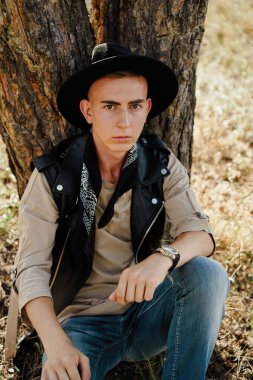 Yakışıklı genç adam rahat kıyafetler ve şık şapka açık havada poz 