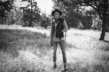 Yakışıklı genç adam rahat kıyafetler ve şık şapka açık havada poz 