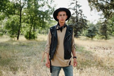 Yakışıklı genç adam rahat kıyafetler ve şık şapka açık havada poz 