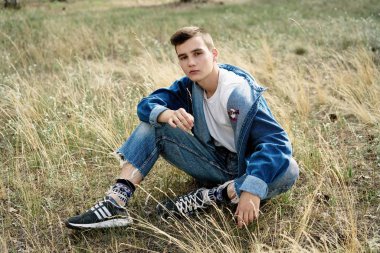 Yakışıklı genç adam açık havada poz rahat denim giysileri 