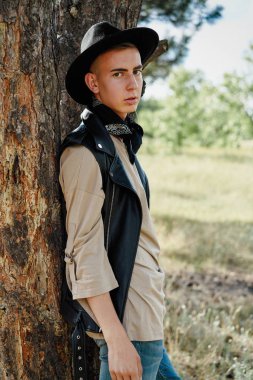 Yakışıklı genç adam rahat kıyafetler ve şık şapka açık havada poz 