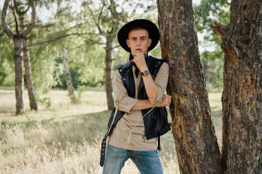 Yakışıklı genç adam rahat kıyafetler ve şık şapka açık havada poz 