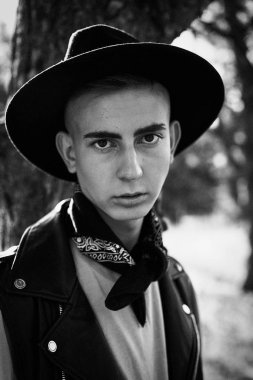 Yakışıklı genç adam rahat kıyafetler ve şık şapka açık havada poz 