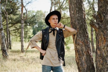 Yakışıklı genç adam rahat kıyafetler ve şık şapka açık havada poz 