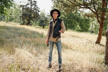 Yakışıklı genç adam rahat kıyafetler ve şık şapka açık havada poz 