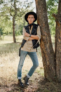 Yakışıklı genç adam rahat kıyafetler ve şık şapka açık havada poz 