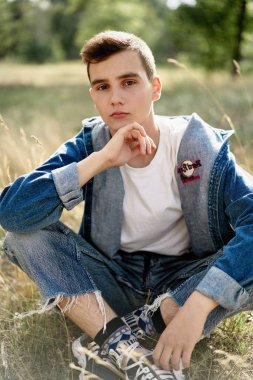 Yakışıklı genç adam açık havada poz rahat denim giysileri 