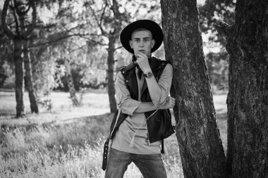 Yakışıklı genç adam rahat kıyafetler ve şık şapka açık havada poz 