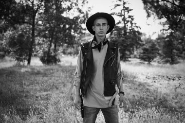 Yakışıklı genç adam rahat kıyafetler ve şık şapka açık havada poz 