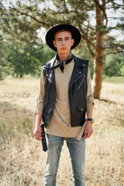 Yakışıklı genç adam rahat kıyafetler ve şık şapka açık havada poz 