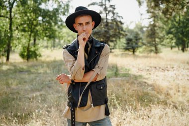 Yakışıklı genç adam rahat kıyafetler ve şık şapka açık havada poz 