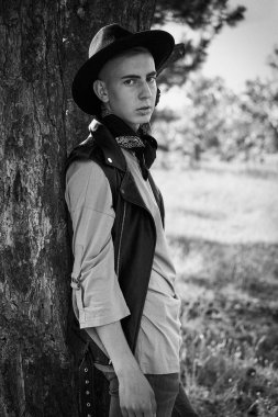 Yakışıklı genç adam rahat kıyafetler ve şık şapka açık havada poz 