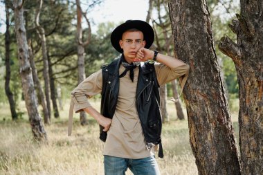 Yakışıklı genç adam rahat kıyafetler ve şık şapka açık havada poz 