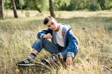 Yakışıklı genç adam açık havada poz rahat denim giysileri 