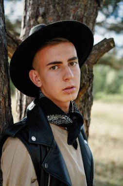 Yakışıklı genç adam rahat kıyafetler ve şık şapka açık havada poz 