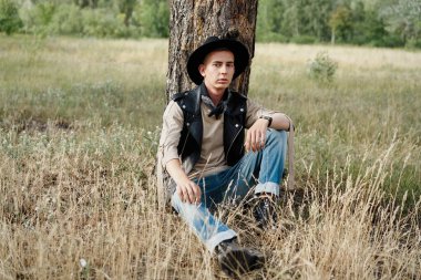 Yakışıklı genç adam rahat kıyafetler ve şık şapka açık havada poz 