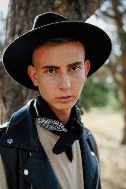 Yakışıklı genç adam rahat kıyafetler ve şık şapka açık havada poz 